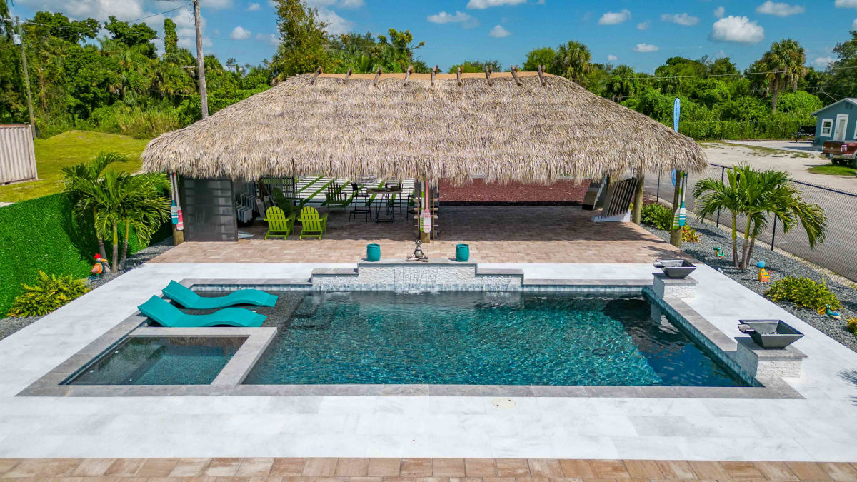 Large pool in fromt of a tiki seating area